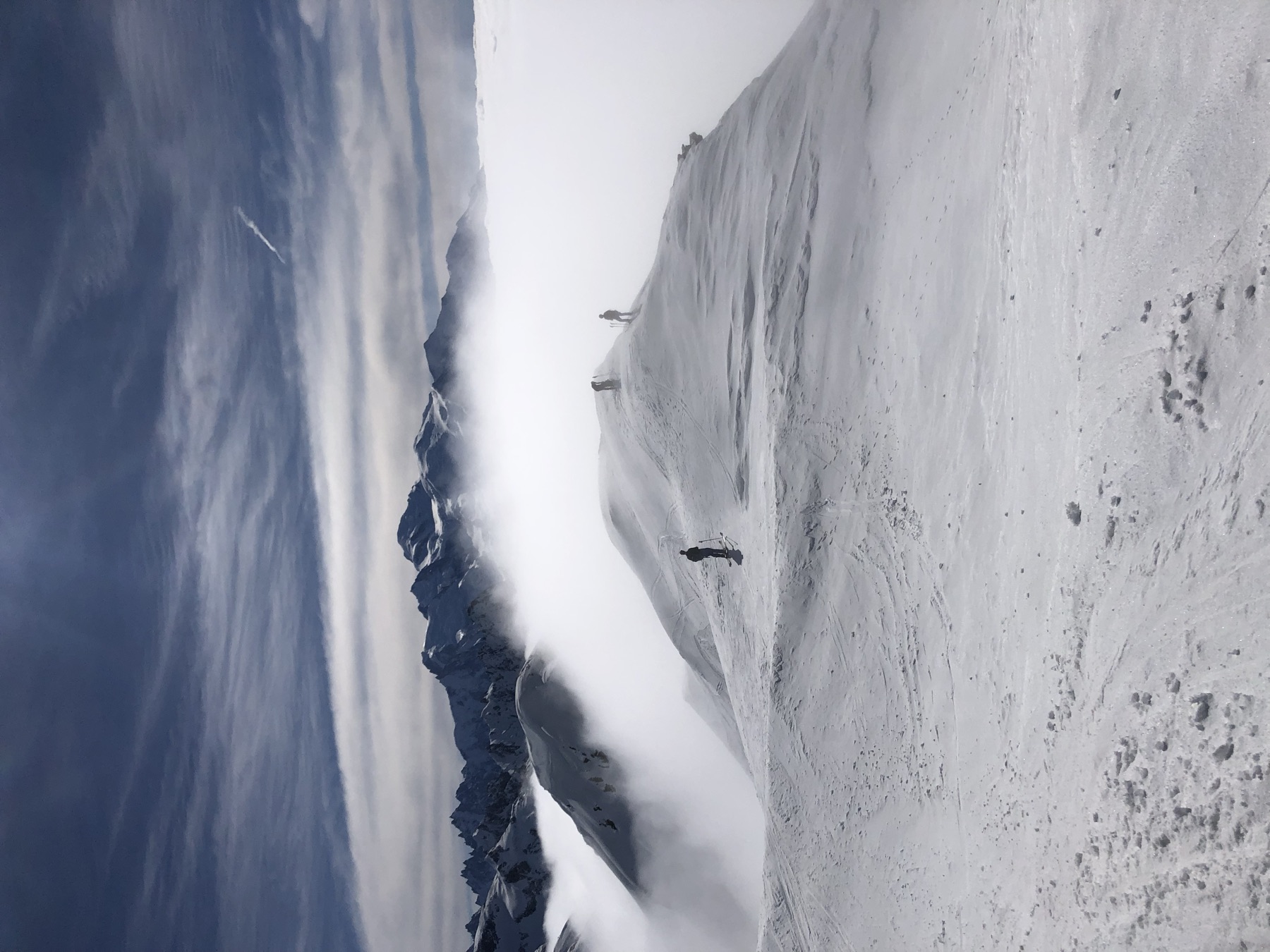 Skiers on a ridge above a sea of clouds